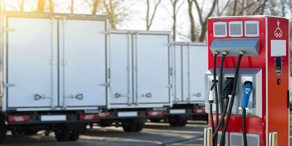 Electric vehicles charging station on a background of a row of trucks. Concept